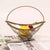 This fruit basket features a transparent glass body paired with a brass twisted rope handle and engraved decorative...