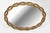 Large oval giltwood mirror, the frame with pierced interlacing ribbons. The gilding, slightly mellowed with age, settles...