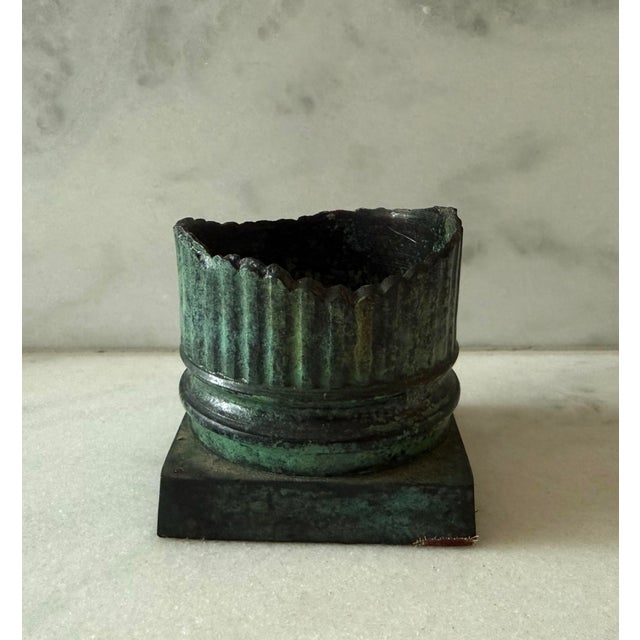 Vintage metal (likely bronze) cylindrical candle holder with green patina and uneven edge on a square base. Could be used...