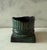 Vintage metal (likely bronze) cylindrical candle holder with green patina and uneven edge on a square base. Could be used...