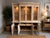 Two-piece display hutch and buffet cabinet beautifylly crafted in a soft neutral finish with timeless architectural...