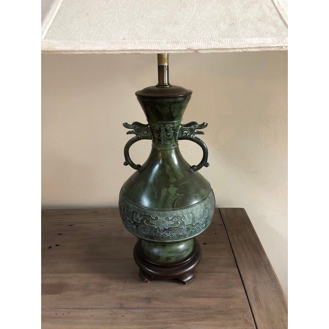 Hollywood Regency style beautiful and vintage bronze table lamps in the form of a Chinese archaic vase on a wood base....
