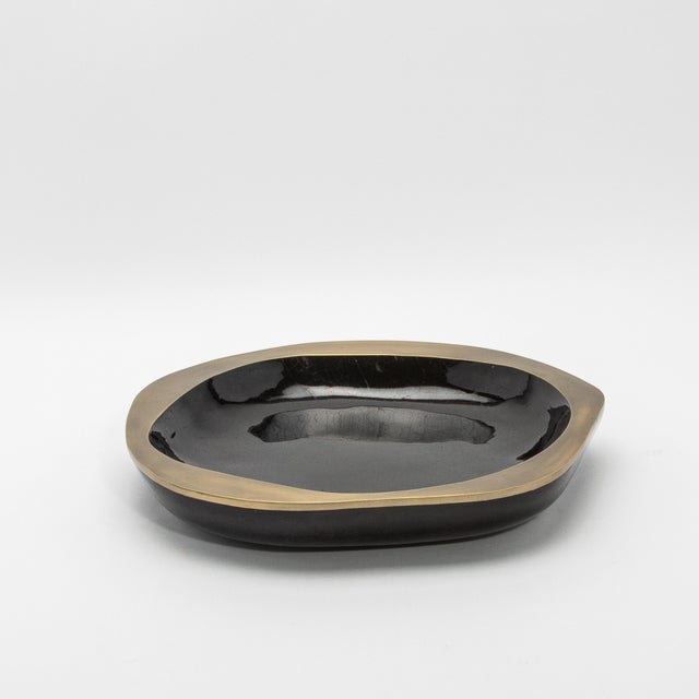 The Lily Bowl in black shell and bronze patina brass details by R&Y Augousti exudes refined elegance through its fusion of...