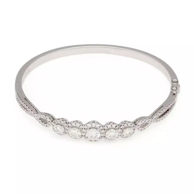 This is a stunning diamond bangle, crafted from 18k white gold with a high polished finish featuring a front half set with...