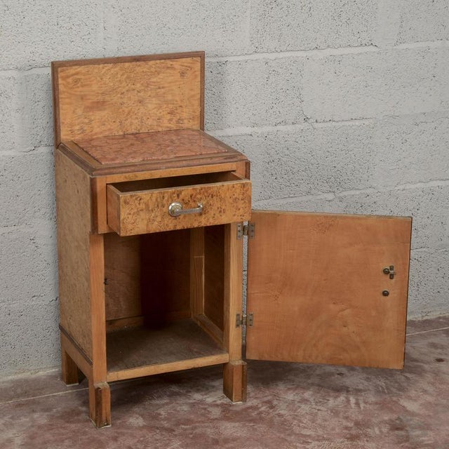 A vintage Art Deco nightstand dating from the 1930s, characterized by a compact silhouette with an elegant, contoured back...