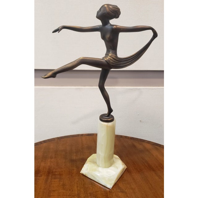 An attractive 20th Century Art Deco cold painted bronze figure of a naked dancer with her arms outstretched in an elegant...