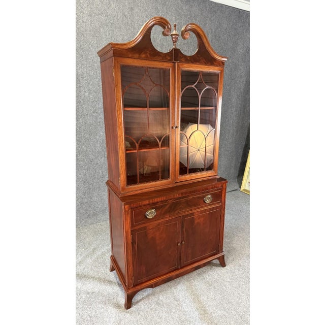 This 1960s vintage mahogany bookcase features elegant Chippendale-inspired lines, arched fretwork glass doors, and a...