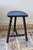 Antique tripod stool in turned wood, with a crescent-shaped seat and a beautiful worn black patina that reveals the wood...