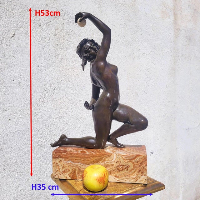 A beautiful patinated bronze dancer on a marble base: in a graceful pose, she playfully passes a ball from one hand to the...