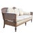 French provincial style cane back sofa with a carved wood frame, woven cane panels, cream striped upholstery, and round...
