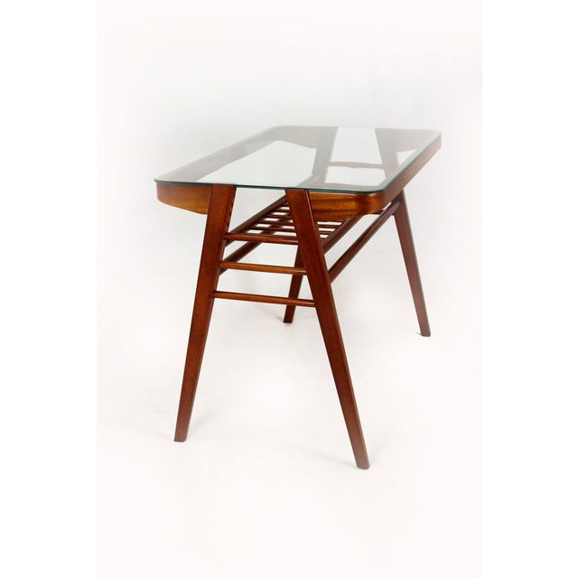 A mid-century coffee table combining a wooden frame with a glass top, designed by František Jirák in the 1960s in...