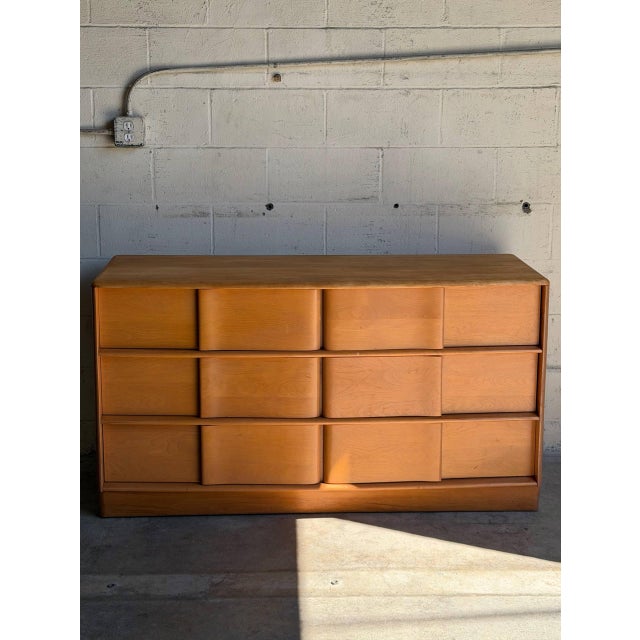 This vintage chest of drawers features a substantial rectangular profile outfitted with twelve spacious storage...