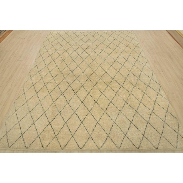 A contemporary Moroccan rug hand-knotted with an all-wool pile on a cotton foundation. This area rug features an all-over...