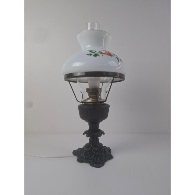 A mid-century cast-iron and glass table lamp produced in czechoslovakia, featuring a sculpted iron base and a hand-...