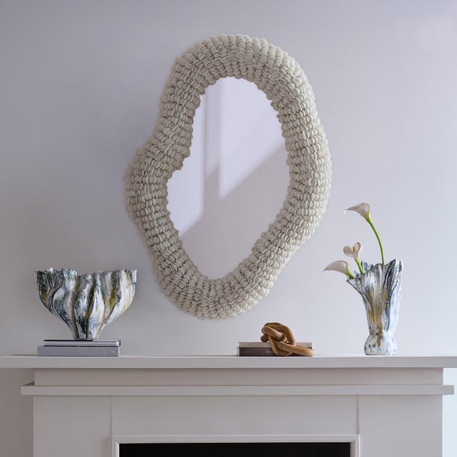 Hand-carved mango and acacia wood beads, each with a soft, shell-like sheen, delicately frame this mirrors fluid shape....