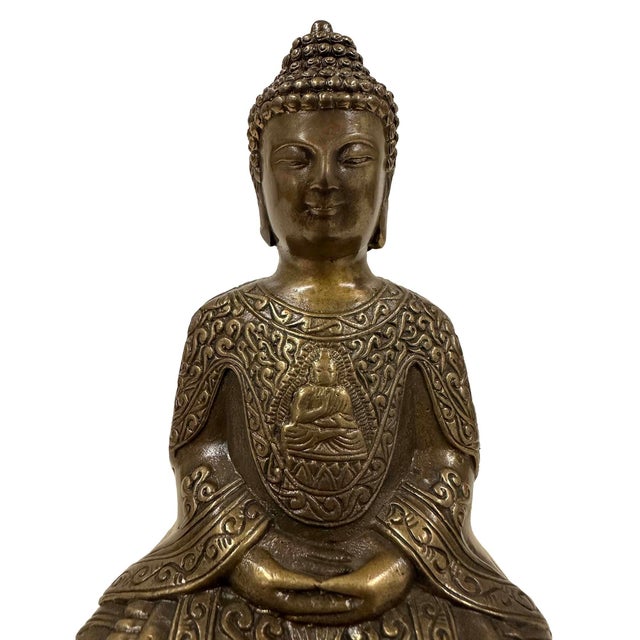 This image shows a bronze-cast Buddha statue, likely depicting Shakyamuni or Amitabha Buddha. The figure is seated in a...