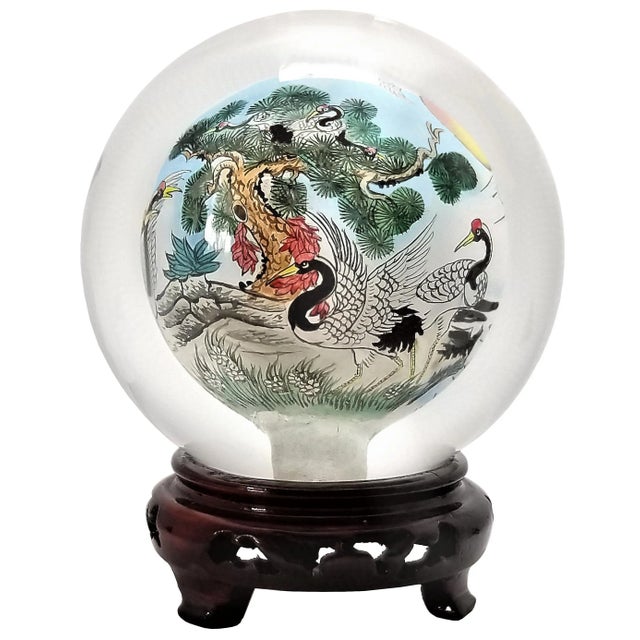 Offering a Chinese glass crystal ball on a wood stand, circa Mid 20th Century. This amazing spherical sculpture is made of...