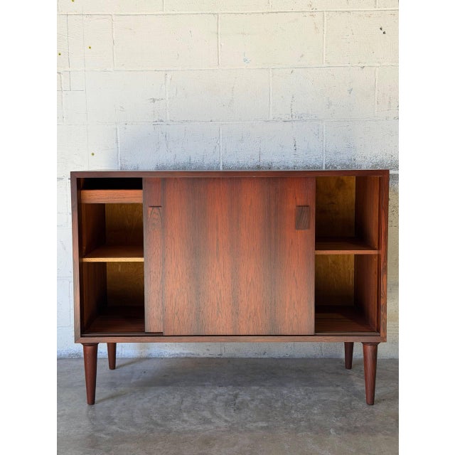 This Danish credenza sideboard features smooth sliding doors opening to reveal adjustable interior shelving and a felt-...