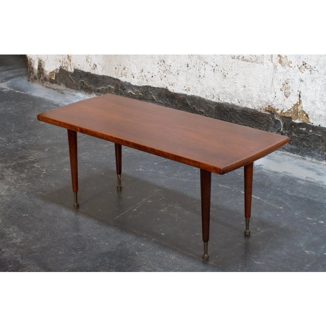 Swedish MCM Mahogany coffee table with turned legs and brass caps on the feet. The tabletop is in excellent condition and...