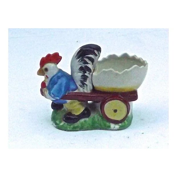 Vintage; 1910-1950, porcelain, chicken and cart, egg cup. Depicting a chicken pulling a cart with a depiction of a broken...