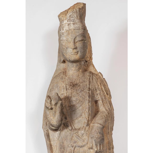 Elegant, carved stone figure of the goddess of compassion and mercy, Kwan Yin. She wears stylized robes and makes a...