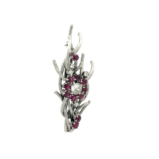 A contemporary brooch showcasing an intricate design with intertwining branches. The piece is adorned with round-cut...