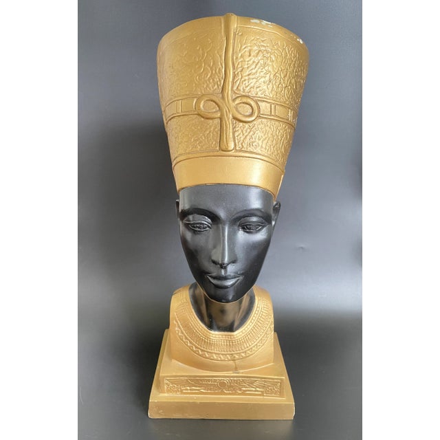 A stunning Egyptian Revival statue of Queen Nefertiti Bust. Crafted from hard resin, finished in gold and black paints....
