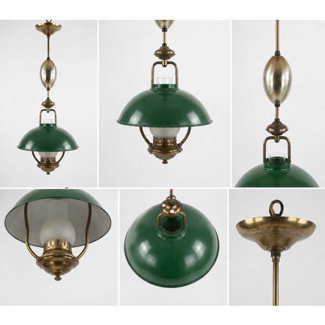 A classic vintage banker’s style hanging pendant lamp featuring a rich green enamel dome shade, warm antique brass finish,...