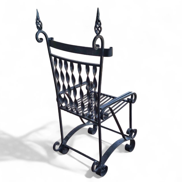 A decorative wrought iron, artisan-made garden or patio chair in a Medieval Gothic revival style, featuring ribbon slats,...
