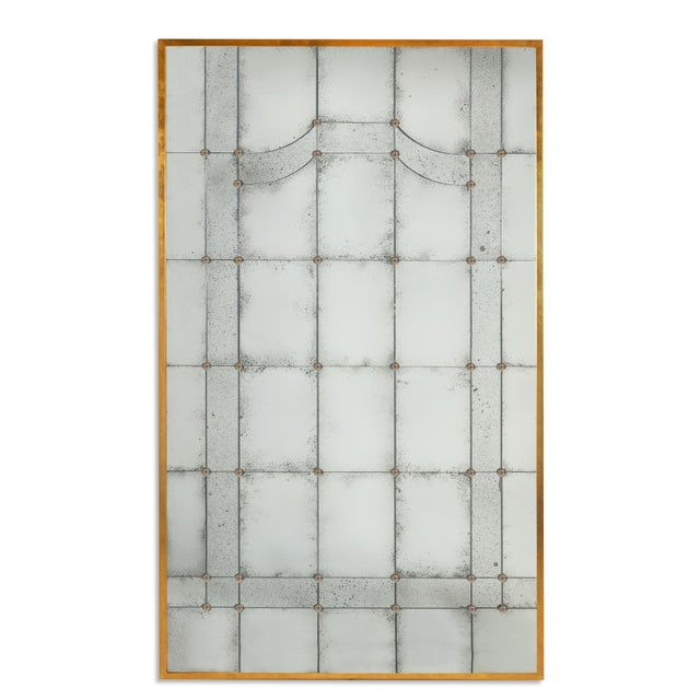 The gilded iron-framed Italian mirror with brass rosettes, holding multiple antiqued mirror panes, reflects the rich...