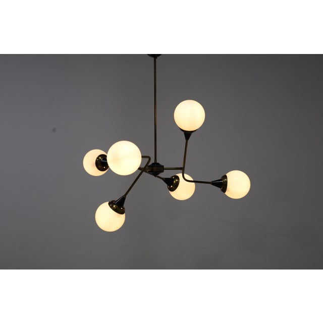 Great looking pair of Stilnovo style chandeliers. Brass frames, black enameled trim, opaque white glass globes. Each light...