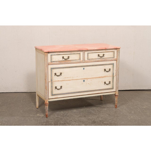 A French Neoclassical-style painted wood chest of drawers, with faux marble top, from the mid 20th century. This vintage...