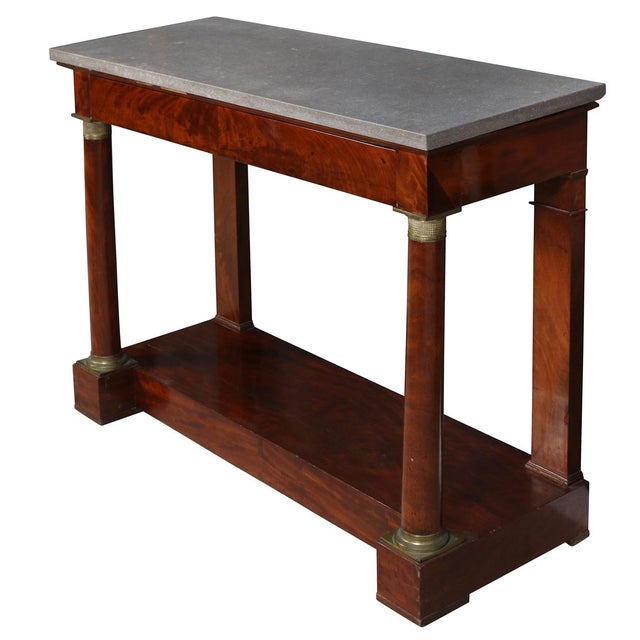 An empire style gray marble top pier console table crafted in richly figured mahogany with restrained gilt bronze mounts...