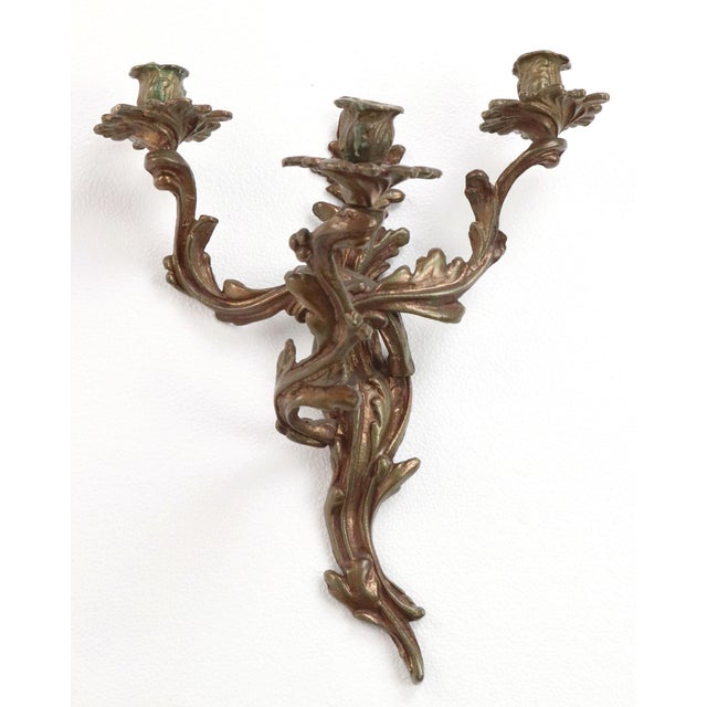Pair of early 20th century Louis XV style wall sconces. Elaborate foliate designs intertwine to support three candle...