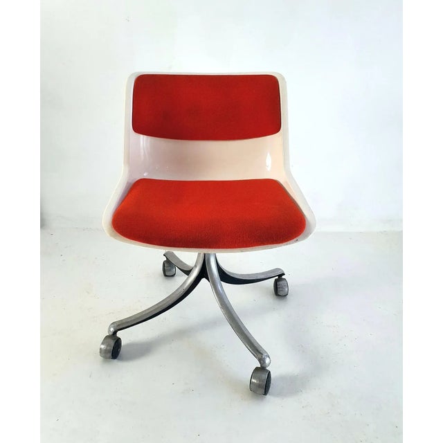 Off white plastic office swivel chair with orange/red wool fabric resting on an aluminium base with the original castors...