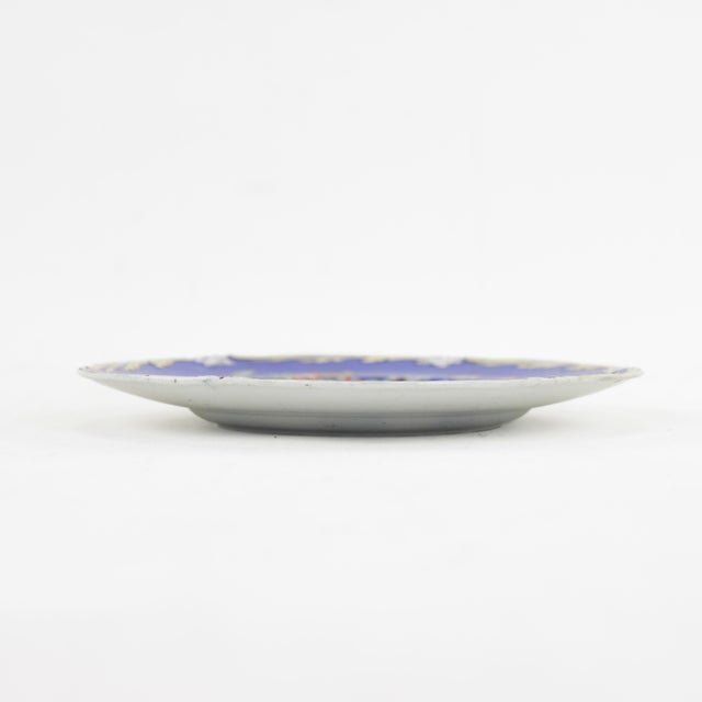 This striking antique porcelain plate boasts a bold royal blue border adorned with delicate gold detailing and an...
