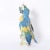 Standout life size porcelain parrot hand decorated in vivid tropical colors, glazed and perched on a tree trunk. Signed...