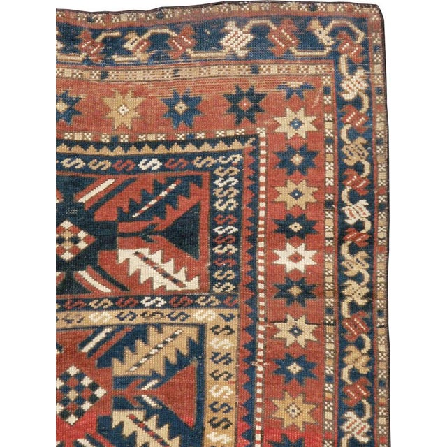 An antique Caucasian Kazak rug from the early 20th century. The warm madder red field is divided into four rectangular...