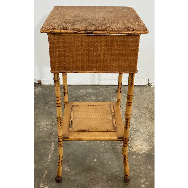 Antique sewing table featuring a rich scorched bamboo finish with woven top and lower shelf surface. Top opens by hinge to...