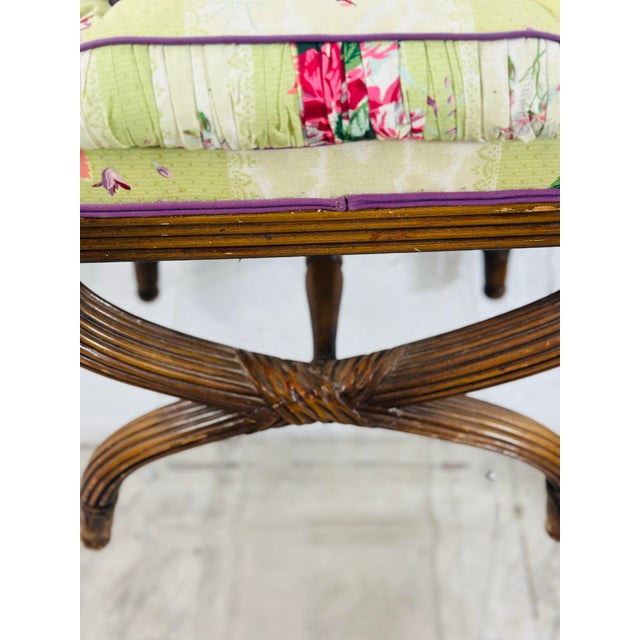 A charming vintage carved wood X-base stool or ottoman featuring elegantly curved, reeded legs joined by a central crossed...