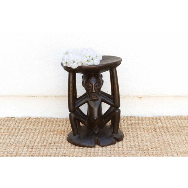 A stunning piece of African art, this antique tribal stool showcases intricate hand-carved figures of a man and a woman...