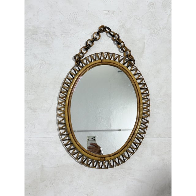 Oval wicker and bamboo wall mirror, 1960 Features a distinctive spiral wicker perimeter and a curved bamboo frame. The...
