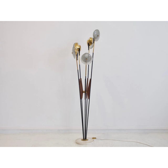 This floor lamp is made of black-painted metal, polished brass, and wood over a marble base. It was produced by Stilnovo...