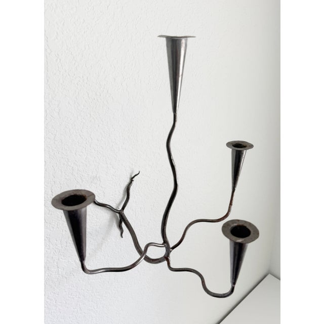 Sculptural mid-20th-century hand-forged wall sconce candle holder. Featuring an aged steel finish and four taper candle...