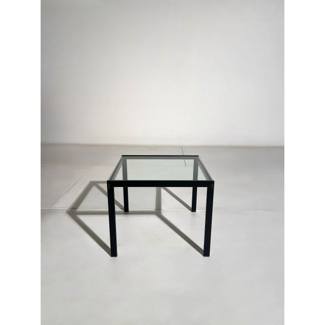 Coffee table featuring a linear black painted metal frame and a clear glass top. Its balanced proportions and clean lines...