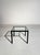 Coffee table featuring a linear black painted metal frame and a clear glass top. Its balanced proportions and clean lines...