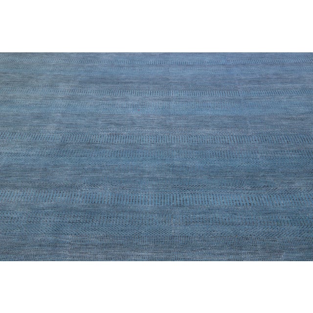 This elegant hand-knotted rug is made of wool and features a subtle blue color scheme accented by an all-over geometric...