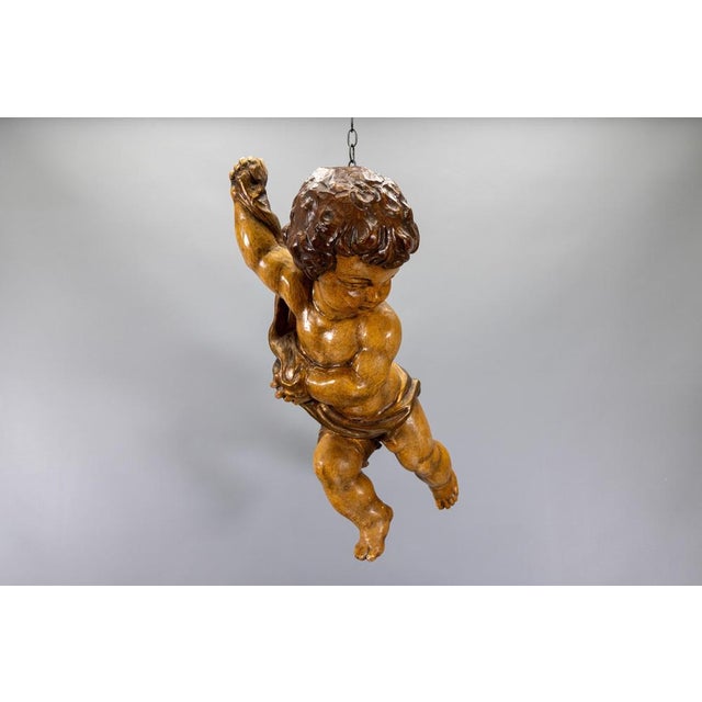 German Baroque Revival carved wooden putto, mid-20th century. Expressive hand-carved and polychromed wooden putto depicted...