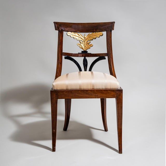 Biedermeier side chair with an upholstered seat and a stained beechwood frame. The unusually designed backrest features...