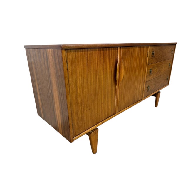 Elevate your space with this stunning 1960s Mid-Century Modern walnut sideboard by Stanley. Showcasing warm walnut grain,...